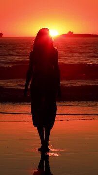 Attractive Asian woman enjoys a walk on the beach at sunset in Southern California. Slow Motion. Vertical Video.