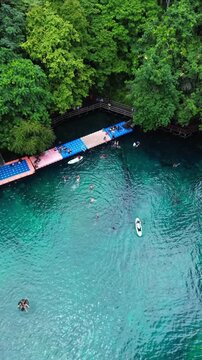 Aerial drone top down view of Labuan Cermin Lake Biduk Biduk Berau East Kalimantan, clear turquoise two taste lake with tourists swimming and kayaking