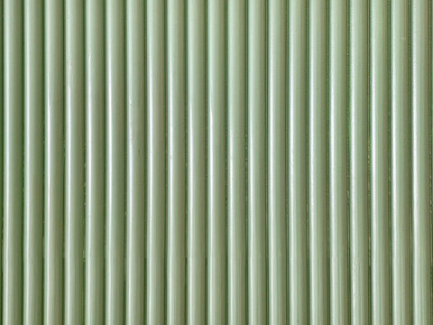 Vertical pattern of parallel light green rounded tubes. Abstract architectural texture with repeating cylindrical shapes, rhythmic lines, and soft highlights. Minimalist sage green wall background.