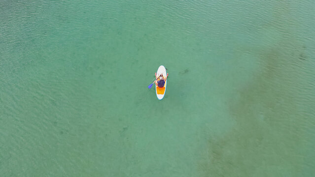 Horizontal aerial top down view of father and little daughter paddleboarding on stand up paddle board in turquoise clear water of Kournas lake in Crete Greece