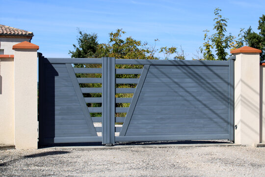 Portail battant moderne automatique en aluminium gris anthracite au design asym&eacute;trique ajour&eacute;