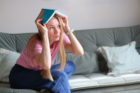 Female reader embracing colorful books on a couch, illustrating love of literature, knowledge and cozy home leisure.