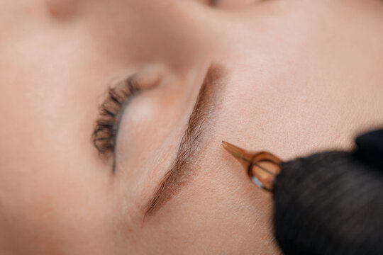 Procedure Permanent makeup tattoo for eyebrows. Detail of beautiful woman with black brows in beauty salon