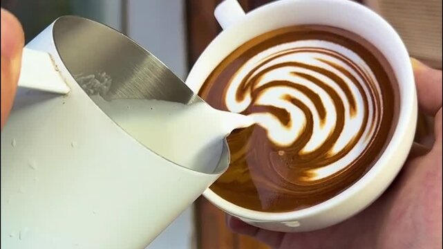 Barista Pouring Steamed Milk to Create Intricate Wave Rosetta Latte Art Pattern in White Ceramic Cup