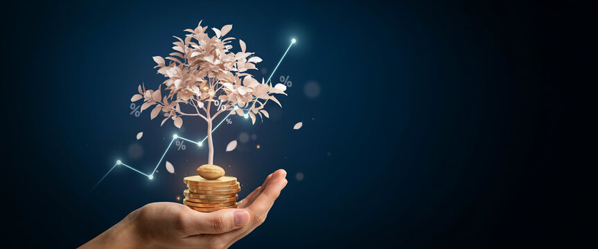 Human hand holding stack of coins with growing money tree and financial chart.