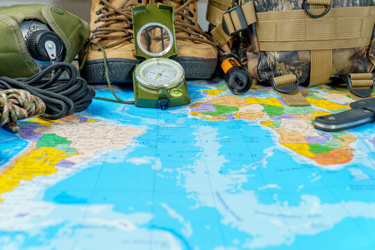 Exploring destinations with essential equipment, compass, hiking boots, backpack, and survival tools on a global map