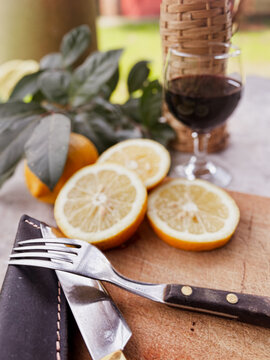 Preparing for an authentic Argentine asado. Featuring a rustic knife and fork set on a wooden cutting board. With fresh lemons and a glass of red wine