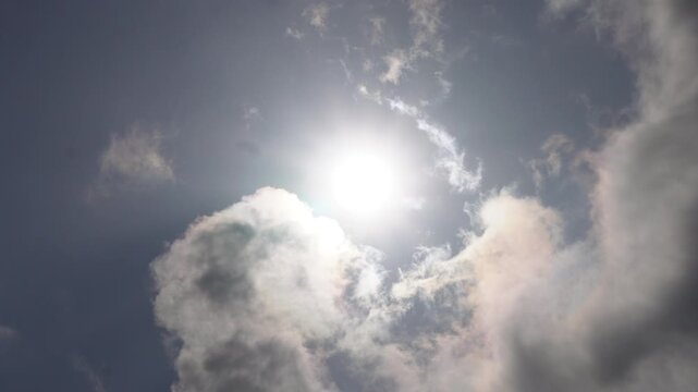 Bright sunlight shining through textured clouds in blue and grey sky