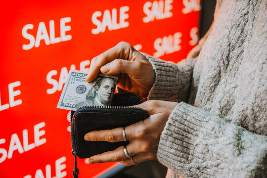 Person taking US dollar banknotes from wallet during sale shopping.