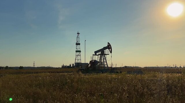 Oil extraction on sunrise. Crude pump jack working on oil field on sunset. Industrial landscape mood. Pumpjack in oil well of oil field on sunrise in Industrial crude area. 
