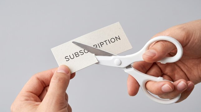 Hands cutting a "SUBSCRIPTION" card with scissors, symbolizing cancellation or termination of subscription services.