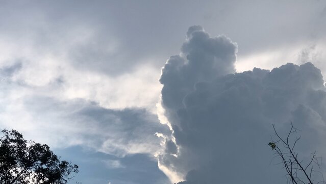 Movement of Beautiful dark rain storm clouds reveals the sun, thunderstorm in dramatic sky, with lens flare. Climate cloudscape scenic. Weather tropical summer squall.
