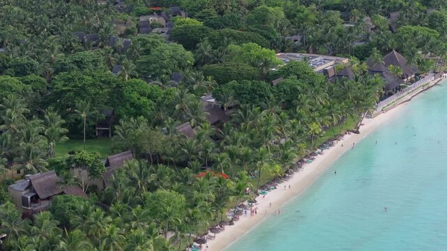 Aerial view of Trou aux Biches Beach with lush palm trees, turquoise water, and boats along the coast in Pamplemousses District, Mauritius.