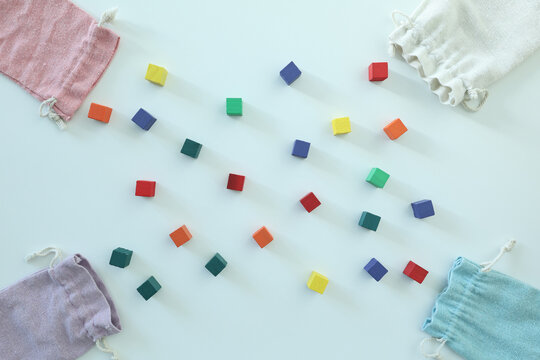 Colorful wooden blocks scattered between pastel fabric bags on a bright background, suggesting play, learning, creativity and early education.