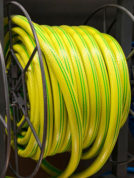 Yellow hose with green stripes wound into a compact coil is displayed in a construction supermarket among products for installation and maintenance work