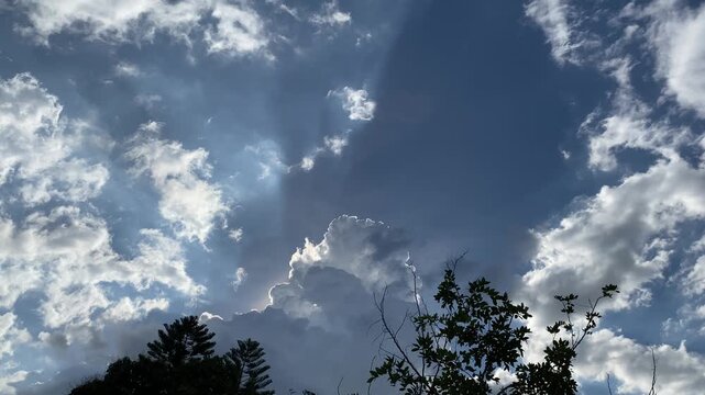 Movement of Beautiful dark rain storm clouds reveals the sun, thunderstorm in dramatic sky, with lens flare. Climate cloudscape scenic. Weather tropical summer squall.