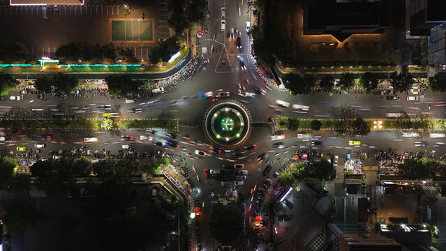 Aerial view of the Simpang Lima roundabout at night with illuminated traffic light trails, surrounding urban buildings, and street lights in Semarang, Central Java, Indonesia.