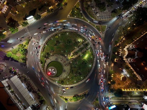 Aerial view of Tugu Muda monument and the historic Lawang Sewu building illuminated at night with traffic light trails circling the roundabout in Semarang, Central Java, Indonesia.