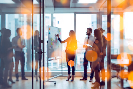 Defocused corporate team brainstorming strategy on whiteboard behind glass with vibrant bokeh reflection