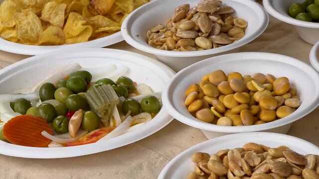 Traditional Spanish tapas snacks including lupin beans, olives, fried almonds, potato chips, and raisins at l escalda festival.