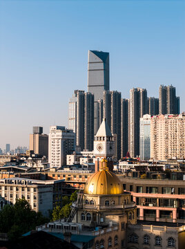 A historic golden-domed building in Wuhan stands in striking contrast to modern towering skyscrapers, beautifully illustrating the city's dynamic evolution from its rich heritage to a vibrant future.