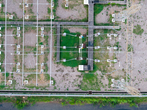 Aerial view of high-voltage main inlet substation with metal transmission towers, power lines, and gravel ground in the Tenaga Nasional Berhad grid, Central Seberang Perai, Penang, Malaysia.