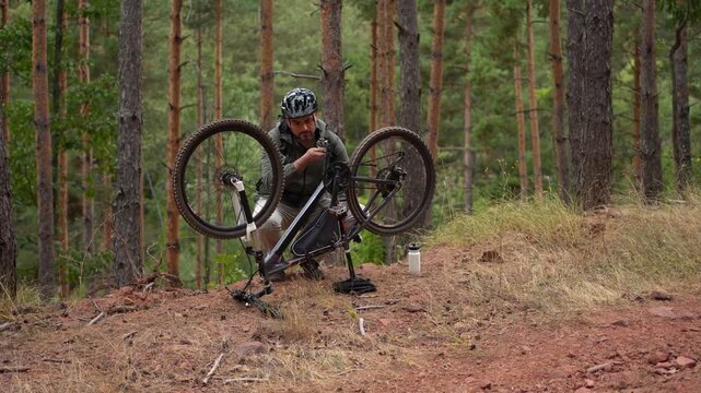 Mountain biker fixes a flat tire in a serene forest setting