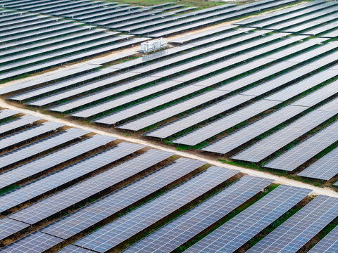 Aerial view of large scale solar photovoltaic power plant with rows of solar panels and a maintenance building in Central Seberang Perai, Penang, Malaysia.