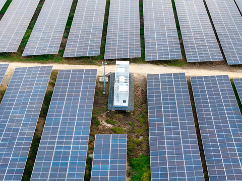Aerial view of a large scale solar photovoltaic power plant with rows of solar panels and a central electrical substation in Central Seberang Perai, Penang, Malaysia.
