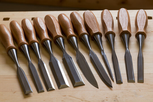 Wood chisels with polished bevels lying on a workbench, woodworking tool detail