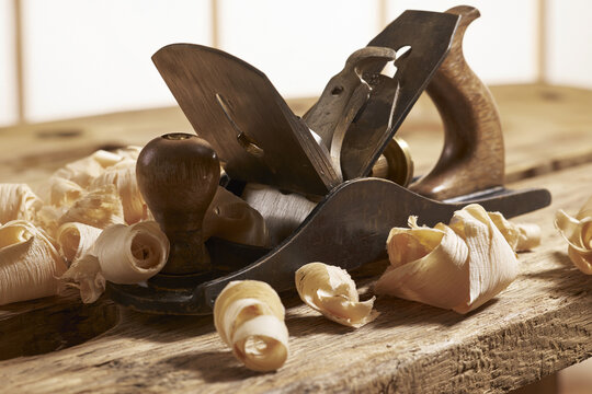 Vintage hand plane surrounded by curled wood shavings, traditional woodworking scene