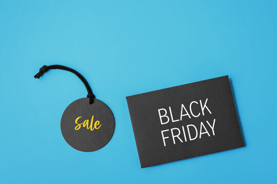 Black sale tag and card with Black Friday text on blue background, copy space