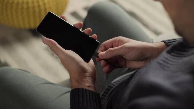 Mobile device charging, man plugging usb-c cable into smartphone for battery power and connectivity