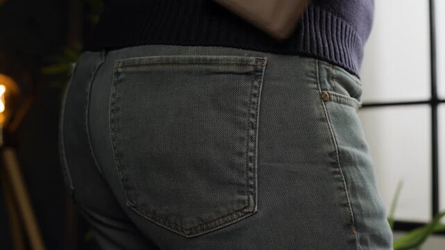 Male hand taking out leather wallet from back pocket of jeans pants, close up view, slow motion