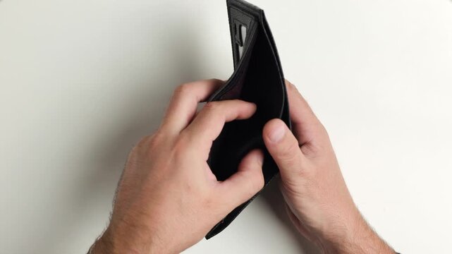 Male hands opening empty black leather wallet, top view of money debt, poverty, inflation and financial crisis concept