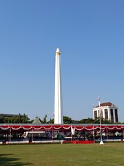 Tall White Obelisk Monument in City Park Under Clear Blue Sky © asyraf