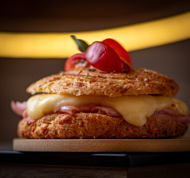 S&aacute;ndwich caliente de chip&aacute; o pan de queso relleno de jam&oacute;n queso fundido y tomate servido en tabla de madera