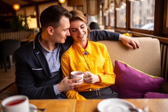 Smiling couple holding a white cup at a restaurant table