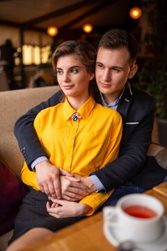 Smiling couple holding a white cup at a restaurant table