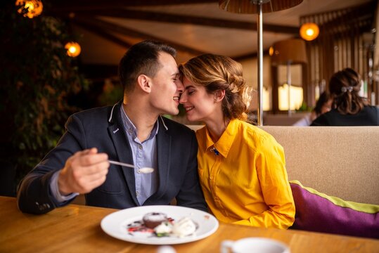 Happy young man feeding a dessert to a woman with a spoon