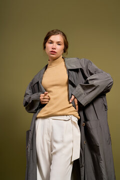 Stylish woman in cozy autumn knitwear and trench coat embracing fall aesthetics in studio