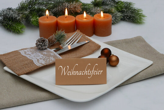 Festlicher gedeckter Tisch zur Weihnachtsfeier mit vier Adventskerzen, rustikaler Jute-Bestecktasche und  einer Karte mit dem Schriftzug 'Weihnachtsfeier'