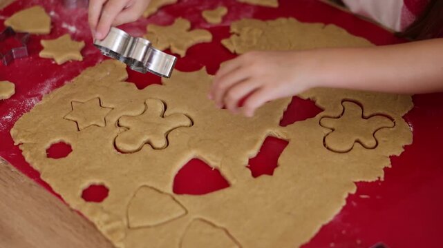Detail of mother and daughter using cookie cutters while making Christmas cookies