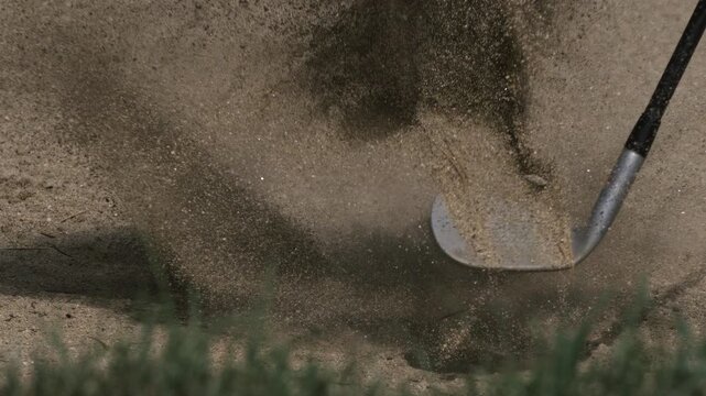 Golf ball struck from a sand bunker in super slow motion, sending a dramatic spray of sand into the air. Cinematic sports footage capturing impact, precision, power and dynamic movement.