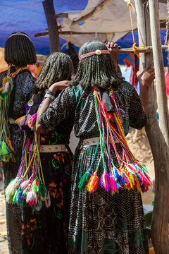 Three Oromo girls embracing with pompoms, Sambate, Ethiopia