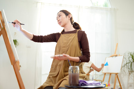 Woman Painting on a Canvas in a Bright Room With Large Windows