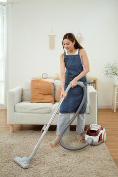 Asian Woman Vacuuming Carpet While Cleaning Bright Modern Home