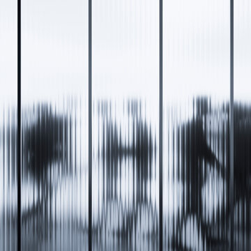 3D abstract human silhouettes distorted through ribbed glass panels in monochrome interior