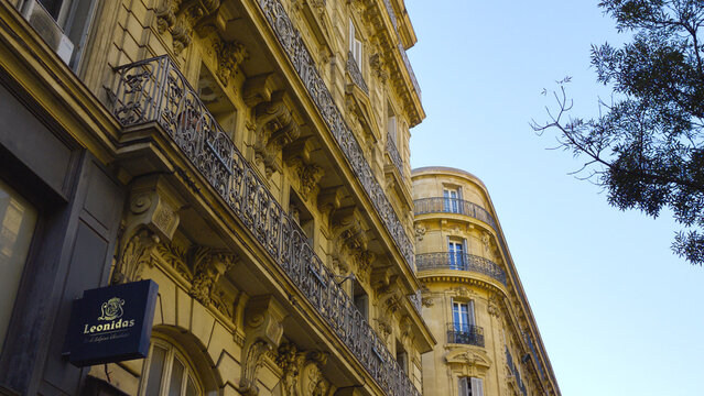 MARSEILLE, FRANCE - SEPTEMBER 16, 2026 - Ornate Haussmann style buildings lining a street with a Leonidas shop in Marseille