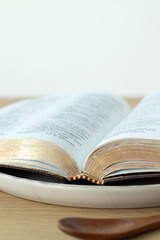 Fototapeta premium Open holy bible book on a plate. Copy space. Christian fasting and spiritual food concept.